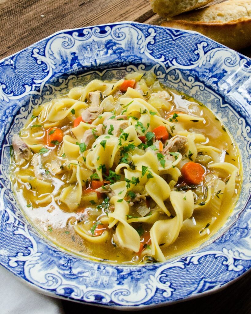 A blue and white bowl of Chicken Noodle Soup.