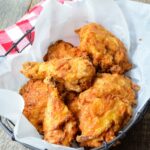 Fried Chicken in a parchment lined basket with red checkered napkin.