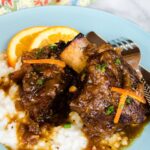 Orange Braised Short ribs on a blue plate with mashed potatoes.