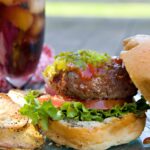 Grilled burger on a bun with lettuce, tomato , ketchup and relish.