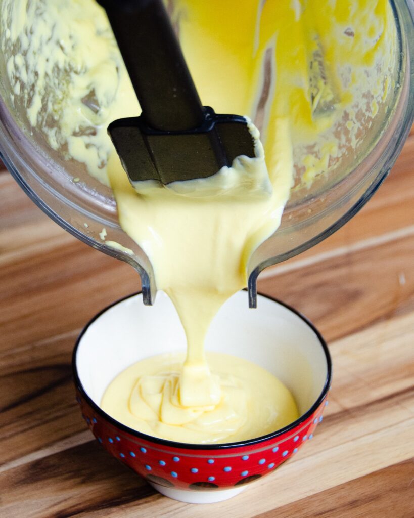Hollandaise sauce pouring out of a blender.