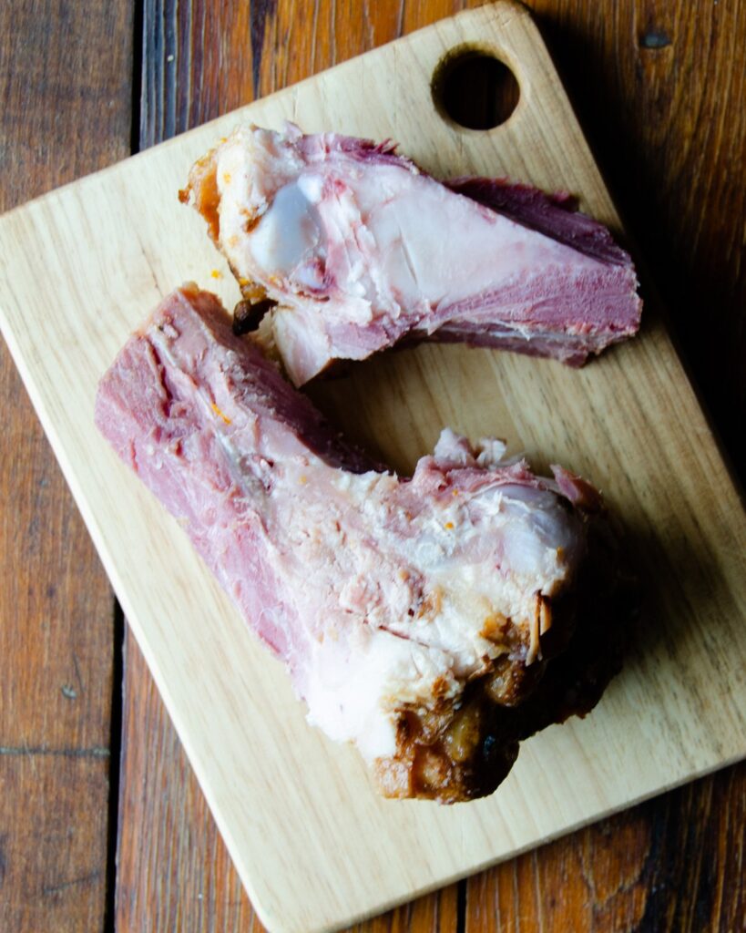 A ham bone on a wooden cutting board - an ingredient in split pea soup.