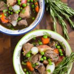 Two bowls of beef stew on a wooden counter.