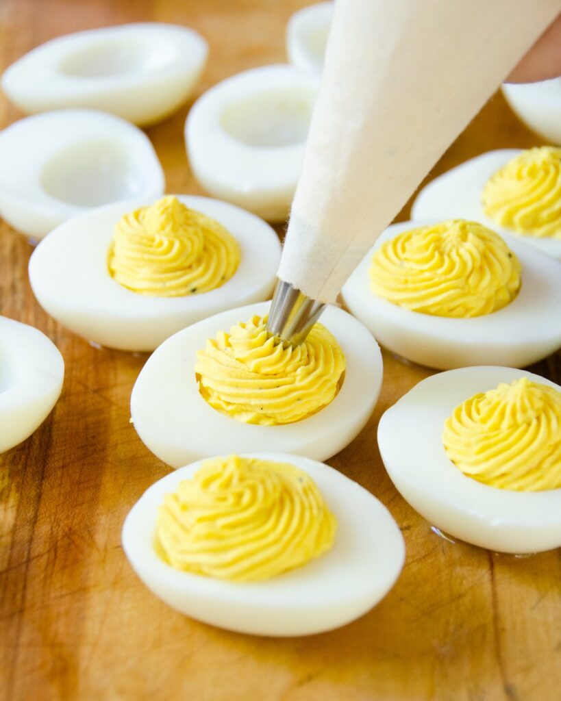 Piping the filling into hard boiled egg whites for deviled eggs.