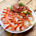 Shrimp Cocktail on a white plate on a wooden table.