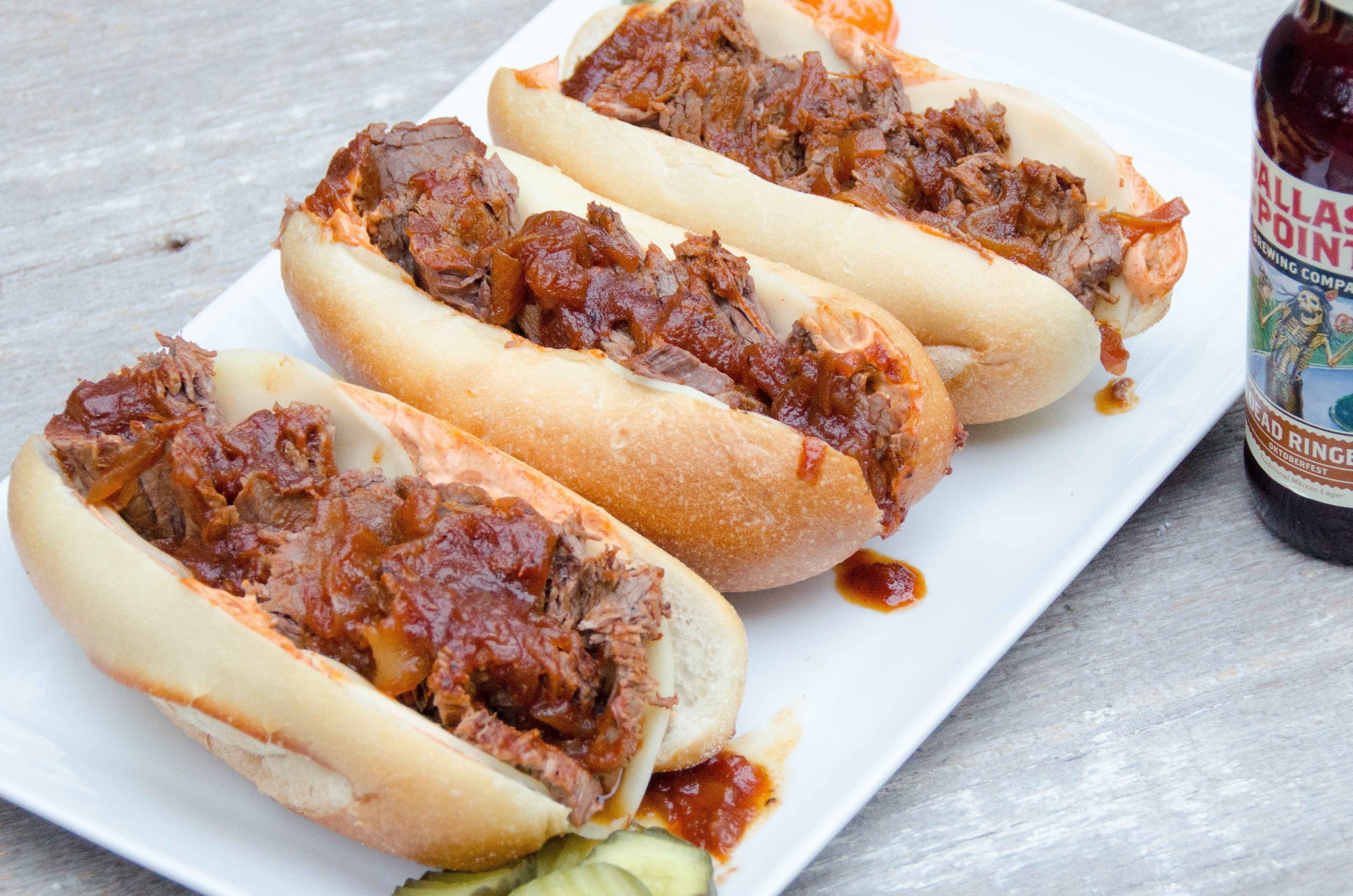 Three BBQ Brisket Sandwiches on a white platter.
