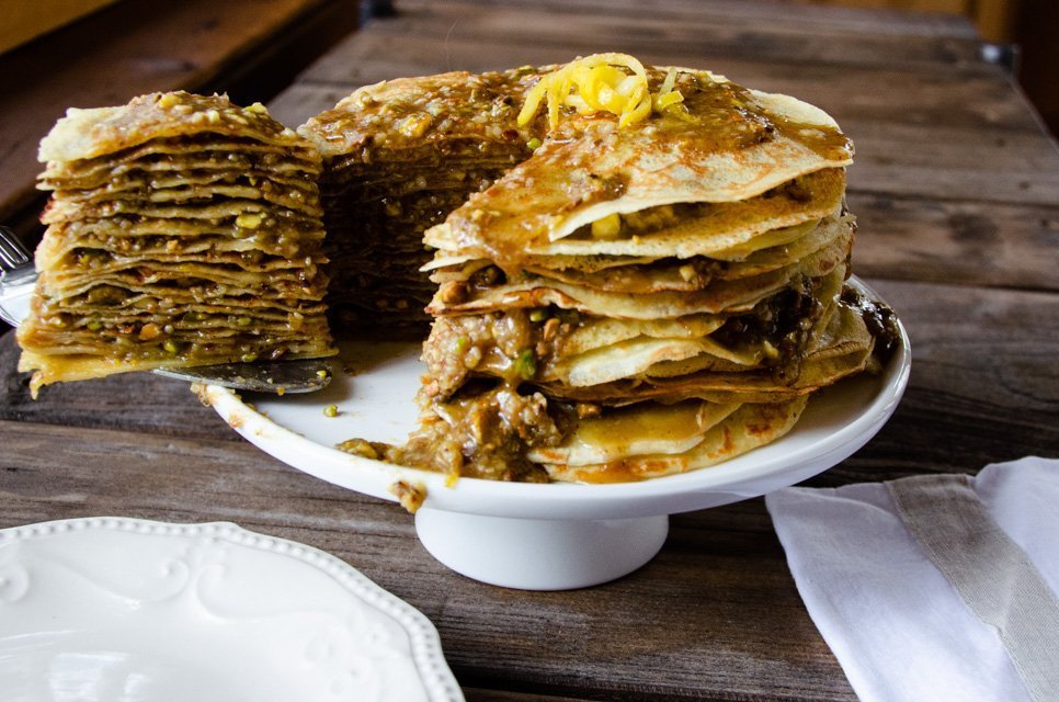 A piece of baklava crêpe cake being removed from the whole cake.