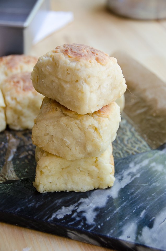 A stack of three buttermilk biscuits on dark marble.