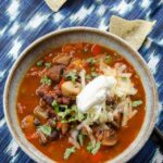 Black Bean Mushroom Chili in a stoneware bowl with tortilla chips.