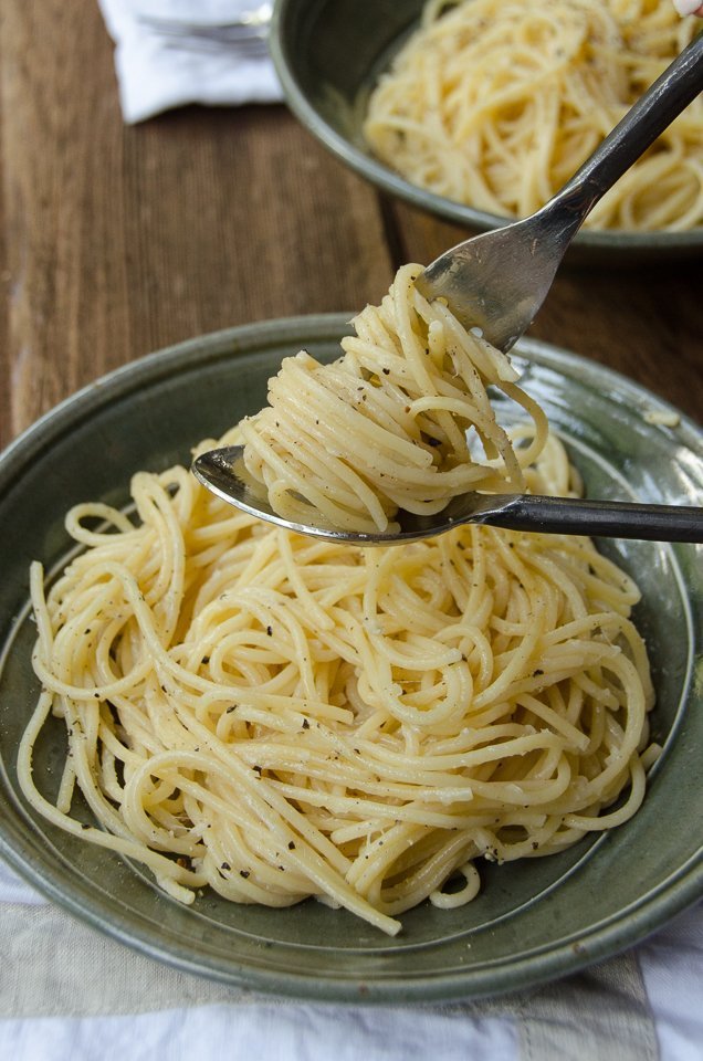 Green bowl with cacio e pepe twirled on a fork.