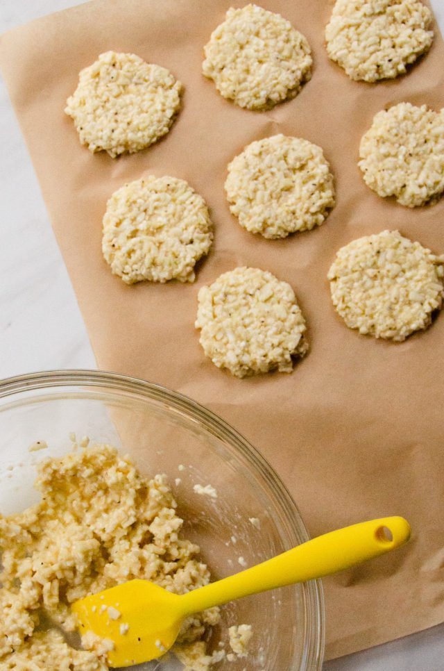 Cauliflower Pizza Bites being shaped into patties on brown parchment.