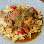 Chicken Cacciatore on a light blue plate with egg noodles.