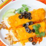Sous Vide Chicken Enchiladas on a white plate with orange striped napkin.