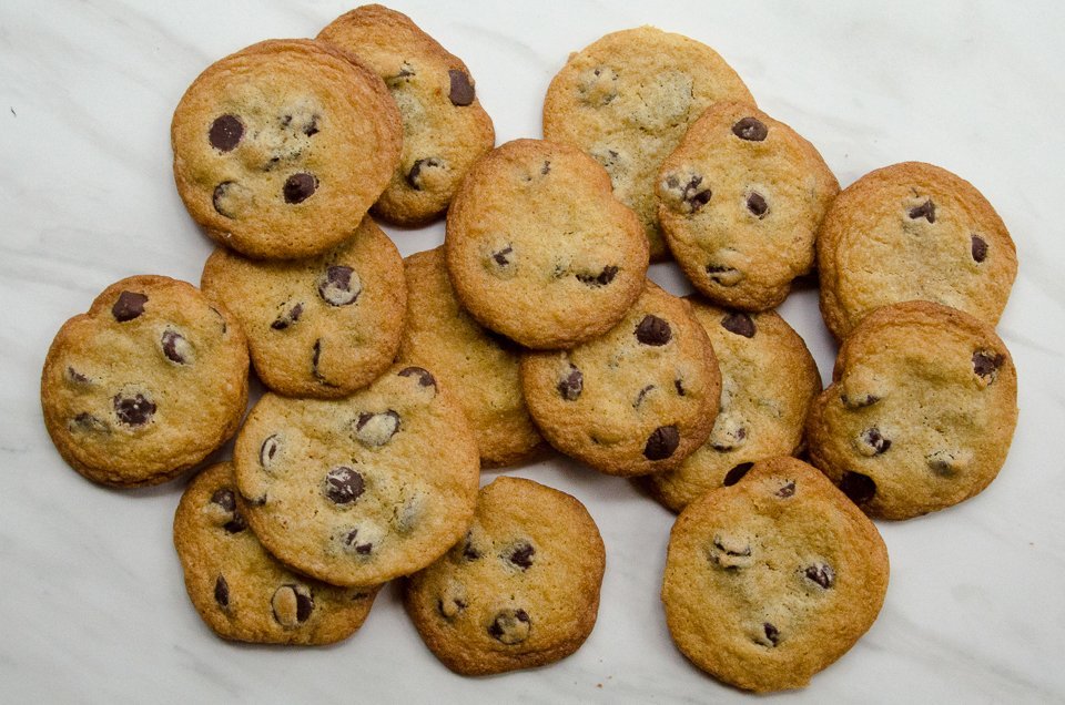 A scattered pile of Chocolate Chip Cookies on a marble counter.