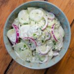 Cucumber Salad in a green bowl on a wooden table.