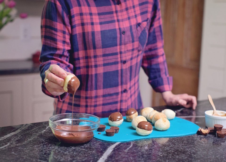 Doughnut holes being dipped into chocolate.