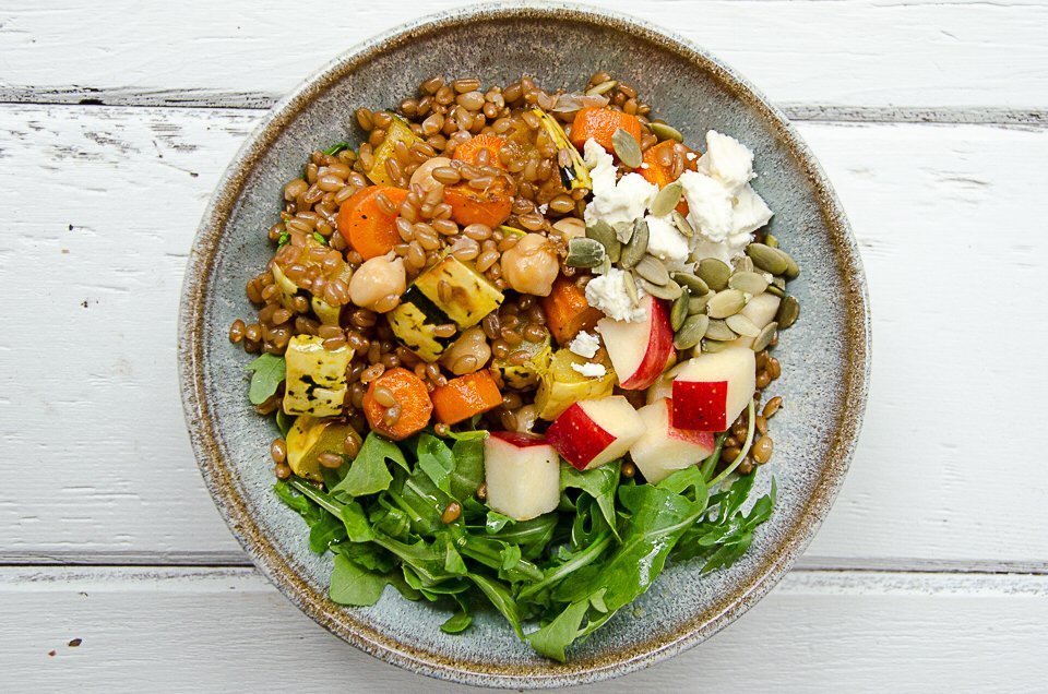 Wheat berry grain bowl on a white wooden table.