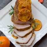 Honeybell Glazed Pork Loin sliced on a square white plate.