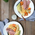 corned beef and cabbage on white plates on a wooden table.
