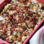 Brussels Sprouts with Horseradish cream in a red baker on a wooden table.