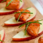 Maple Glazed Salmon Bites with chives on a wooden serving tray.