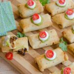 Mini beef and bean burritos on a striped wooden tray.