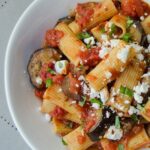 Pasta à la Norma in a white bowl on a grey placement.
