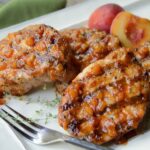 Grilled Pork Chops on a platter with peach BBQ sauce.