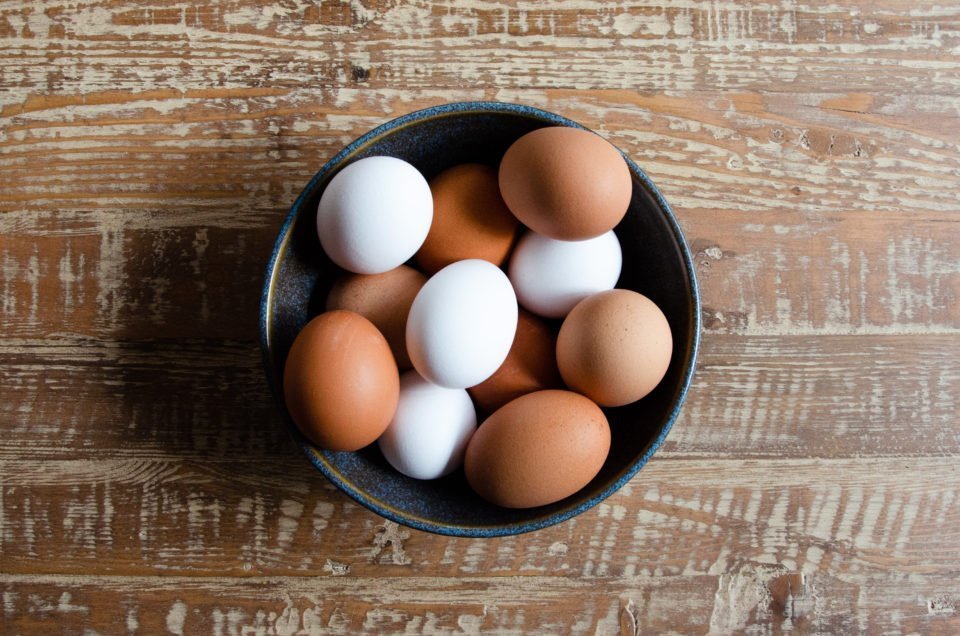 White and brown eggs in a blue bowl.