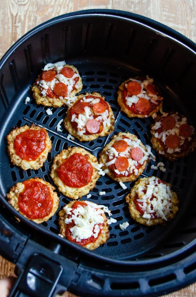 Topped Cauliflower Pizza Bites in an air fryer basket.