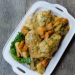Pot Roasted Chicken on a square white platter with root vegetables, all on a wooden table.