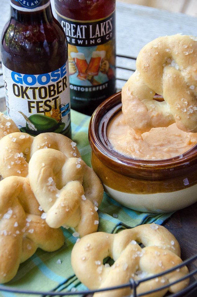 A Soft Pretzel being dipped in a crock of Beer Cheese.