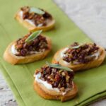 Ricotta Olive Crostini on a green napkin on a marble countertop.