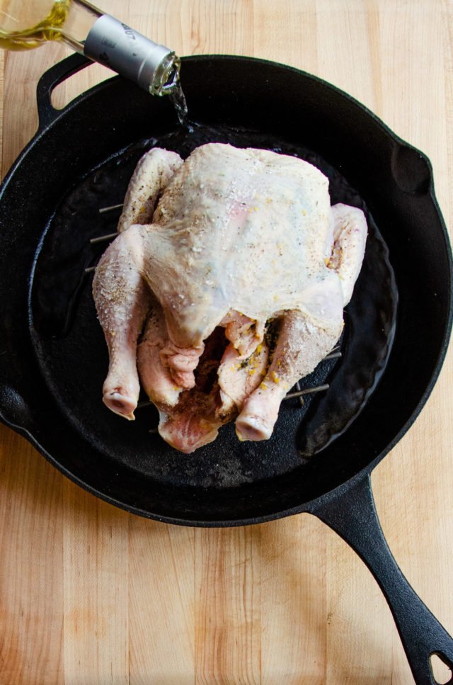 A raw roast chicken in a cast iron skillet.