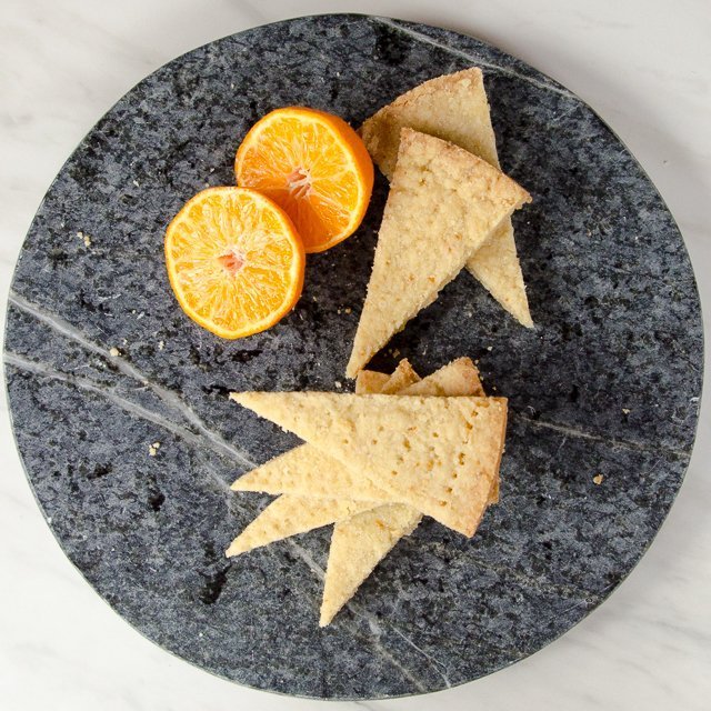 Orange Shortbread Cookies with a halved orange on a soapstone tray.