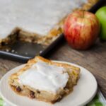 A piece of french apple slab pie with the remainder in the background.