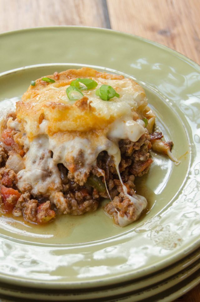 A portion of Sloppy Joe Casserole on a green plate on a wooden table.