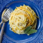 Spaghetti butternut spaghetti on a blue plate with fork and spoon.