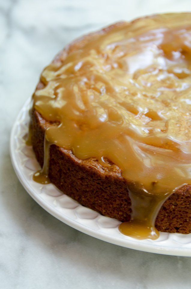 Whole sticky toffee pudding with caramel sauce dripping down the sides.