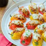 Stuffed baby sweet peppers on a white platter on a wooden table.