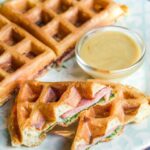 Stuffed waffles on a blue plate with a dipping sauce.