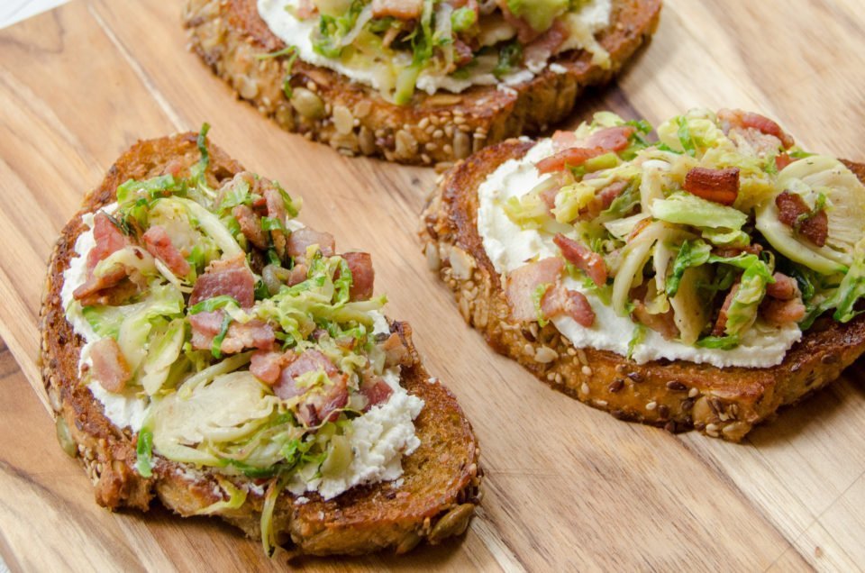 Close up shot of Shaved Brussels Sprouts Toast on a wooden board.