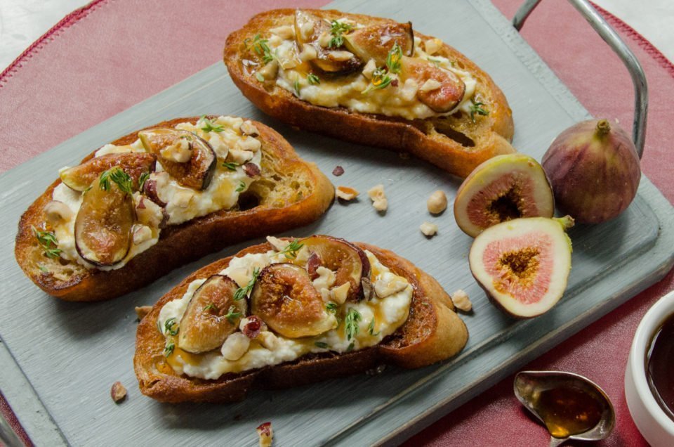 Fig, Honey and Ricotta Toast on a blue wooden cutting board.