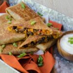 Burrito pockets on a silver tray with orange napkin and dipping sauce.