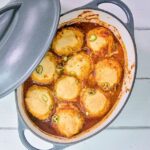 Chili con Carne with Cornbread Dumplings in an oval cast iron Dutch oven on a white table.