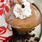 Chocolate espresso mousse in a glass dish on a tray with espresso beans.