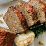 Slices of spicy Italian meatloaf on a white platter.