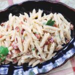 Pressure Cooker Penne Carbonara on a black platter with tomatoes on the side.