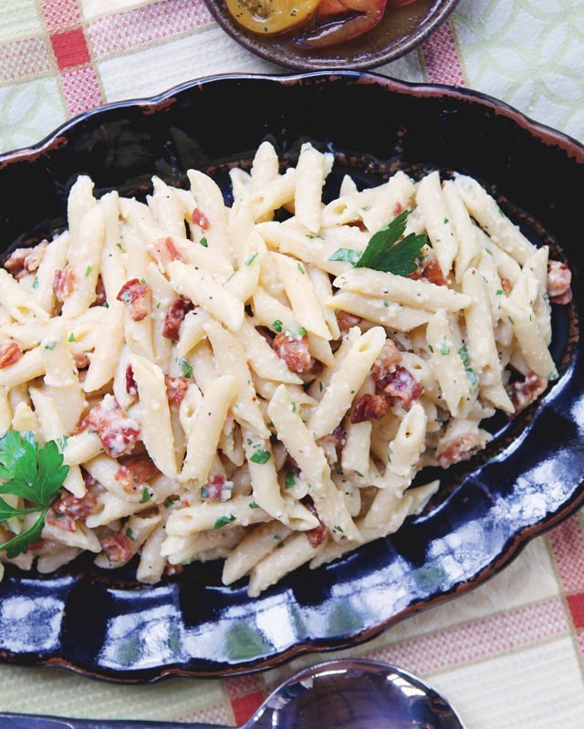 Pressure Cooker Penne Carbonara on a black platter with tomatoes on the side.