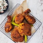 Pickle Brined Fried Chicken in a parchment lined wire basket with pickles garnishing it.